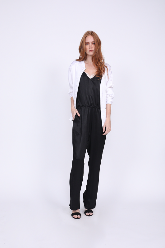 Model is wearing the Hayley Jumpsuit in black with the Megan Camisole in black/dove underneath, and the Hayley Bomber Jacket in bright white on top, worn unzipped.